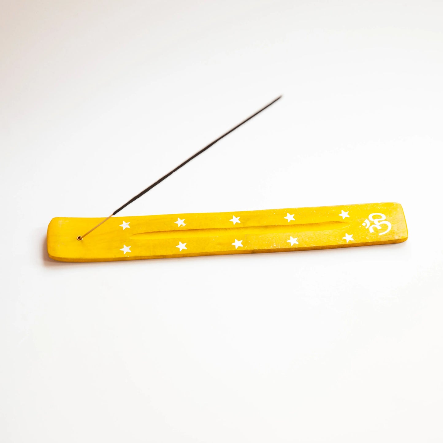 Yellow wooden Artschatz incense holder with white stars and OM symbol, holding a lit incense stick. - Yellow OM with Stars
